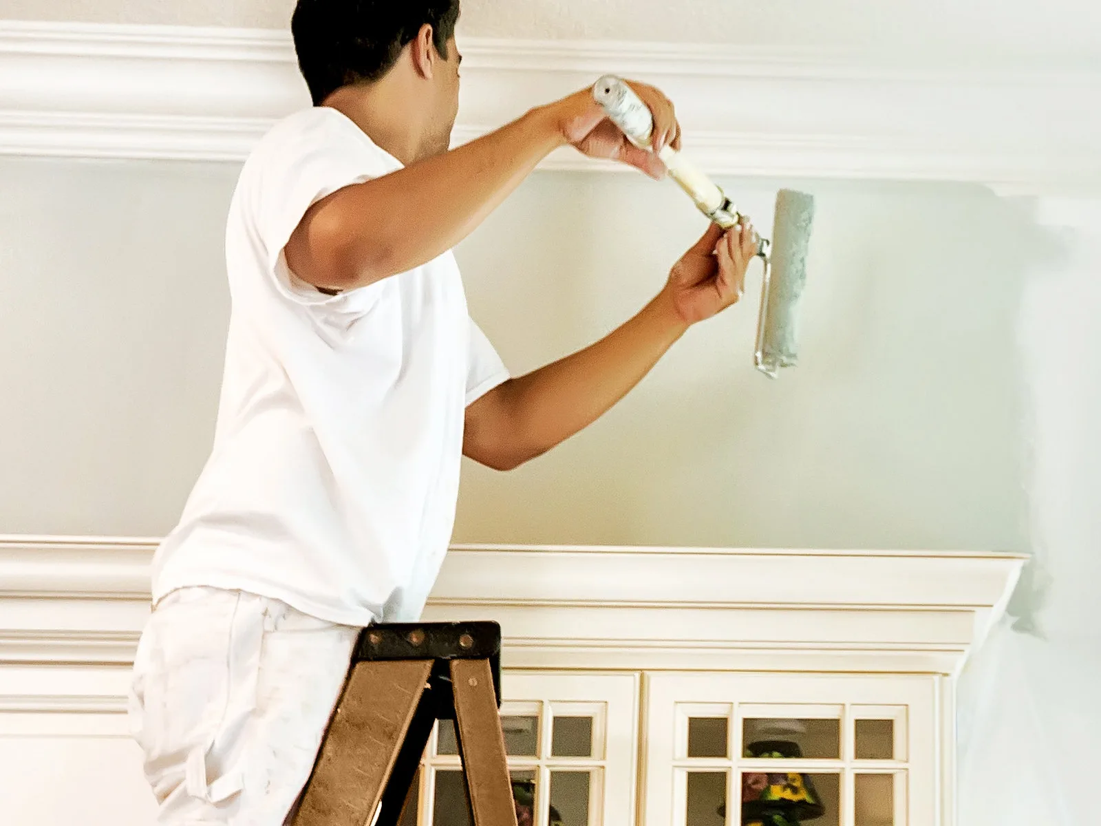 Peintre appliquant une peinture de finition au rouleau sur un mur intérieur